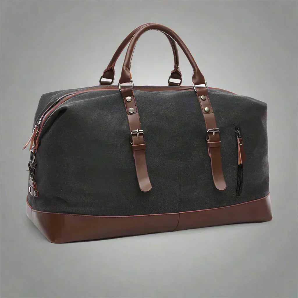 Timeless Travel Carry bag in blue durable canvas with genuine brown leather accents structured silhouette dual top handles adjustable detachable shoulder strap and leather zipper pulls showcasing luxury durable travel styling upscale craftsmanship premium finish and spacious carry on friendly design