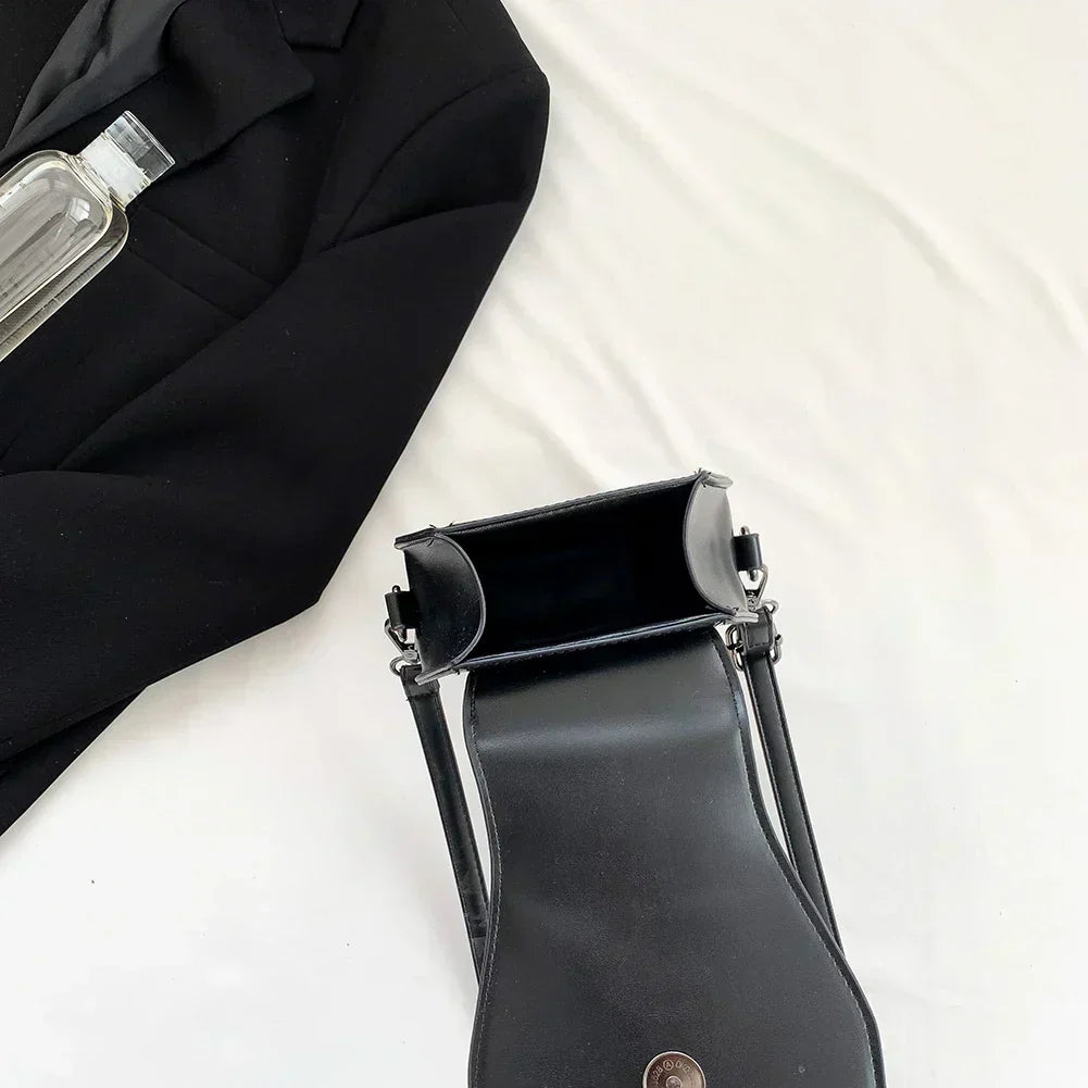 Midnight Edge Crossbody bag in luxury black vegan leather with glossy finish structured silhouette and metal hardware featuring button clasp and compact design showcasing bold unconventional upscale styling and durable premium construction for everyday edge