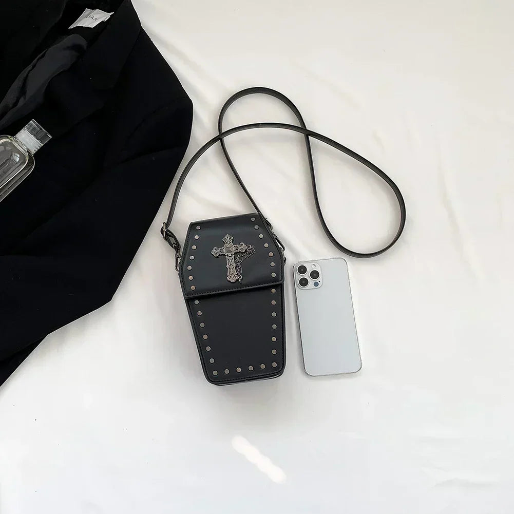 Midnight Edge Crossbody bag in luxury black vegan leather with glossy finish and metal hardware shown beside white smartphone and black garment on white surface featuring structured silhouette showcasing bold unconventional styling and upscale durable premium construction for compact everyday carry