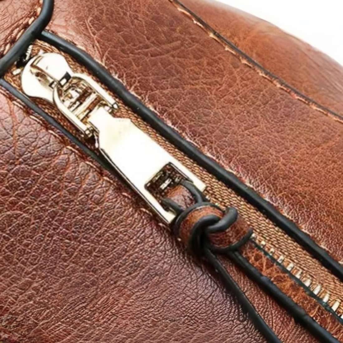 Classic Carry Hobo in brown premium vegan leather showing elegant gold tone zipper with decorative pull tab and clasp surrounded by textured leather and visible stitching showcasing upscale hardware refined detailing and secure everyday functionality and durability