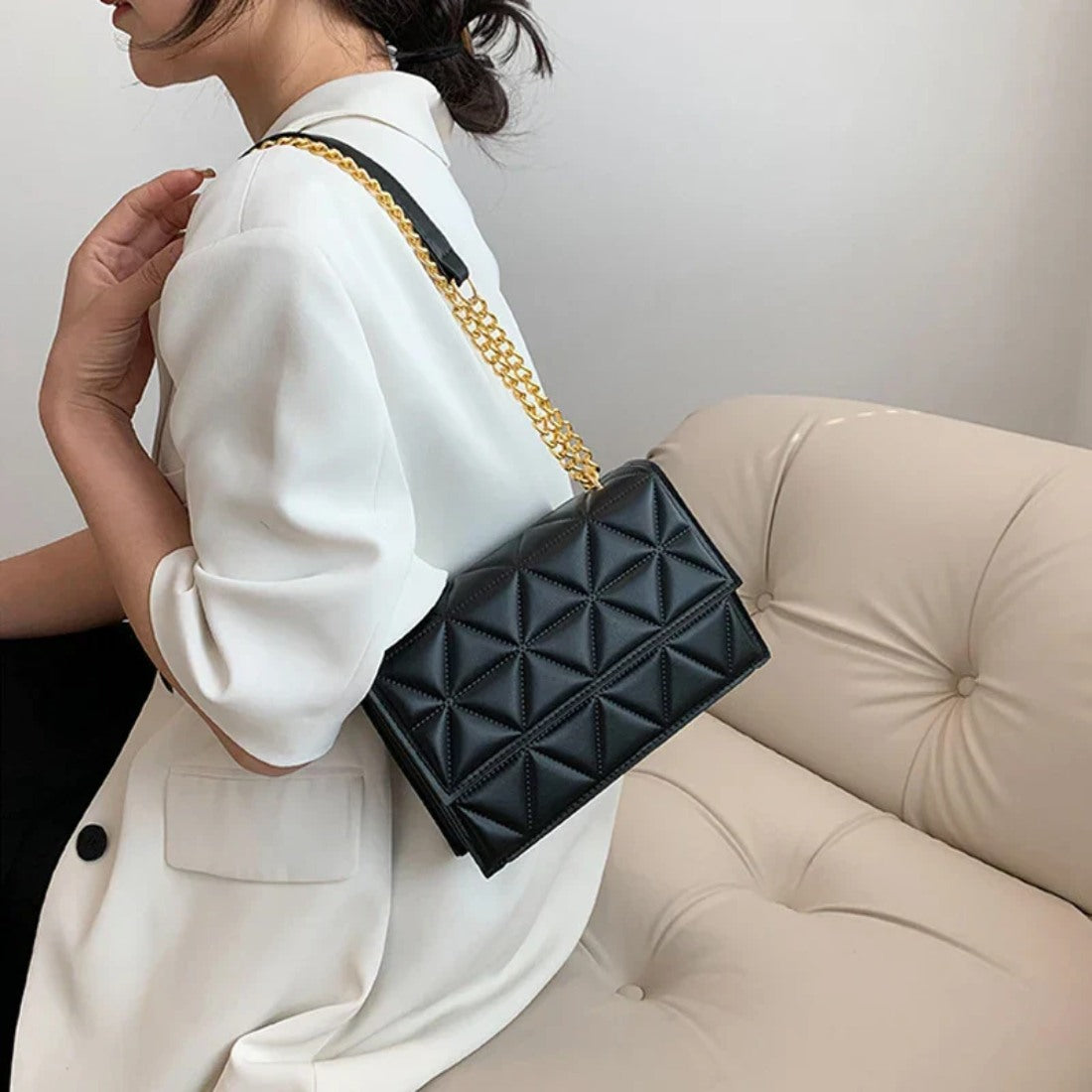 Timeless Chain Crossbody luxury bag in black vegan leather with geometric quilted texture gold chain strap and flap closure worn by model showcasing sleek modern styling polished premium finish and compact everyday sophistication