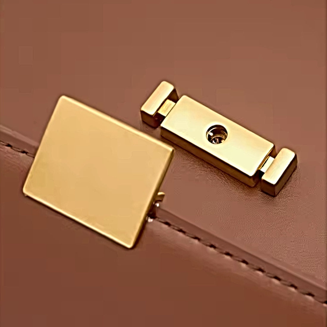 Timeless Charm Satchel close up of upscale gold accent hasp closure on caramel genuine kitt cross grain leather satchel showing rectangular plate locking mechanism and stitched seam detail showcasing luxury hardware upscale craftsmanship and premium finish