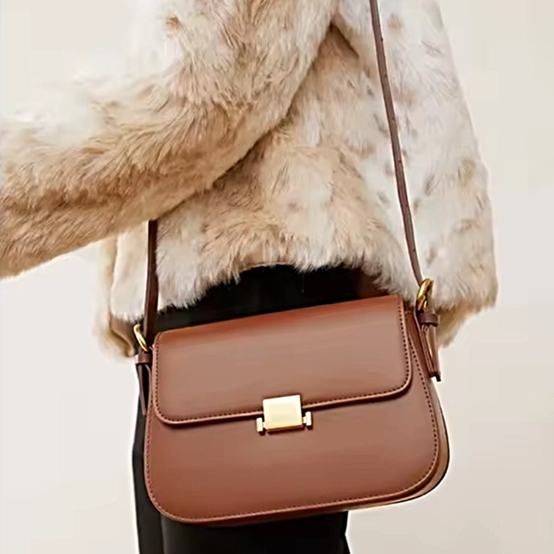 Timeless Charm Satchel in caramel genuine kitt cross grain leather with structured rectangular silhouette flap front design gold accent hasp closure and thin shoulder strap worn by model showcasing luxury styling upscale craftsmanship premium finish and compact everyday elegance
