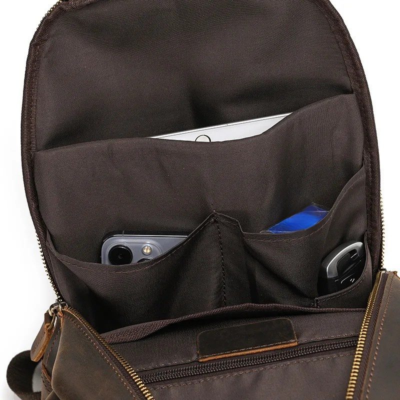 Frontier Leather Sling men's crossbody bag interior showing brown leather, zipper pocket, and organized compartments with phone, keys, and small items inside.