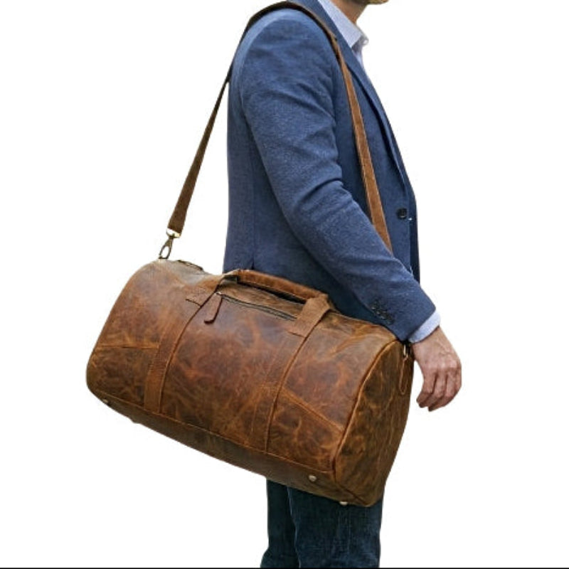 Man carrying horizon leather carry mens brown leather travel duffel bag with an adjustable removable crossbody shoulder strap