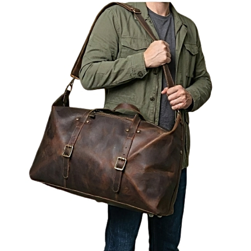 Model holding brown landmark leather weekender leather travel duffel bag with leather shoulder strap