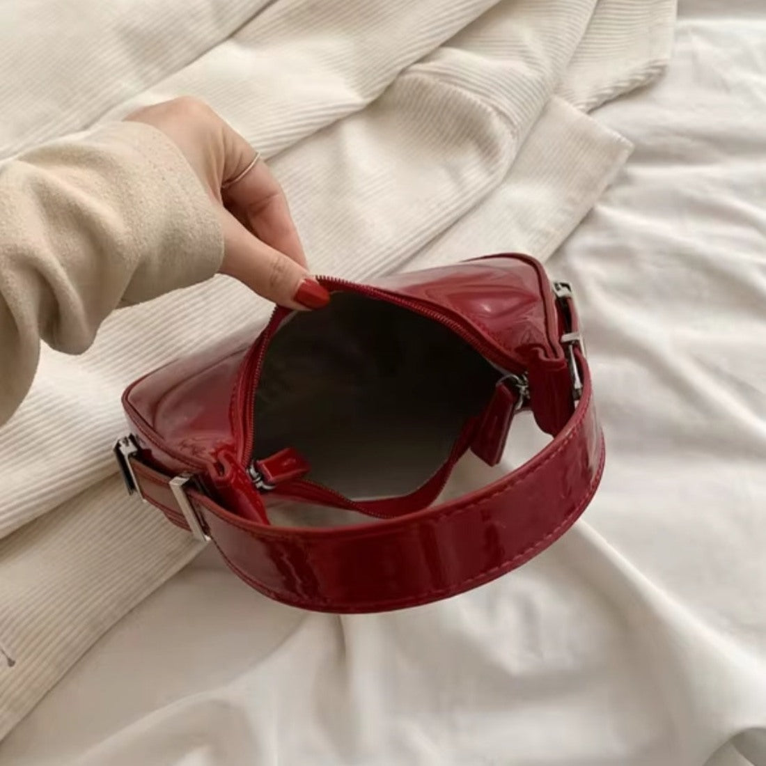 Luna Curve Carry luxury bag in glossy red vegan leather shown open with lined interior silver hardware accents held by model showcasing spacious compartment refined styling and polished premium finish for elevated everyday use