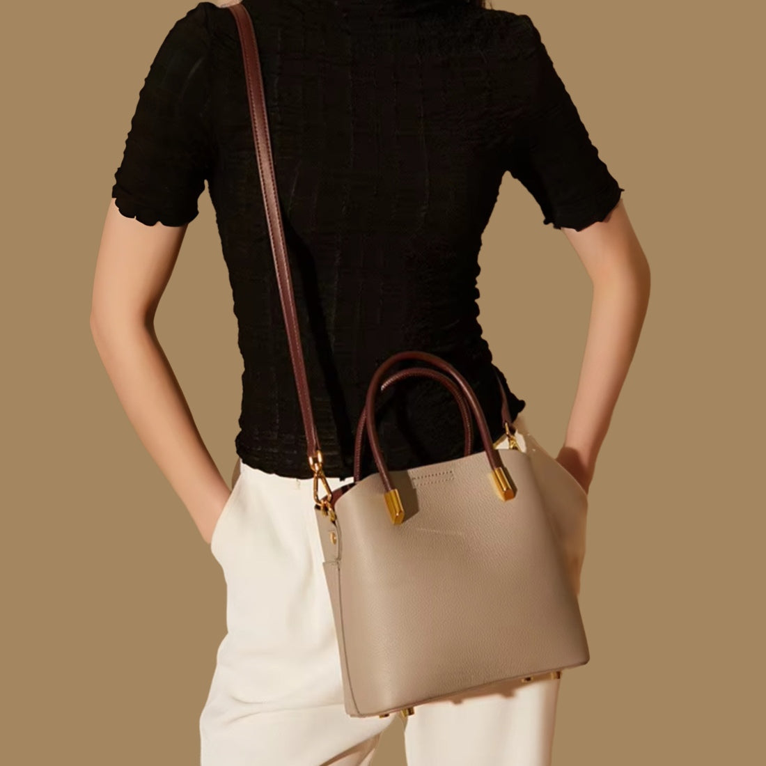 Luxe Bucket Carry luxury beige genuine leather handbag with upscale gold accents and premium adjustable brown genuine leather strap worn crossbody by model