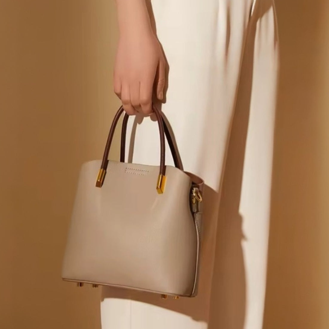 Luxe Bucket Carry beige luxury genuine leather handbag with premium brown handles and upscale gold accents shown handheld by model