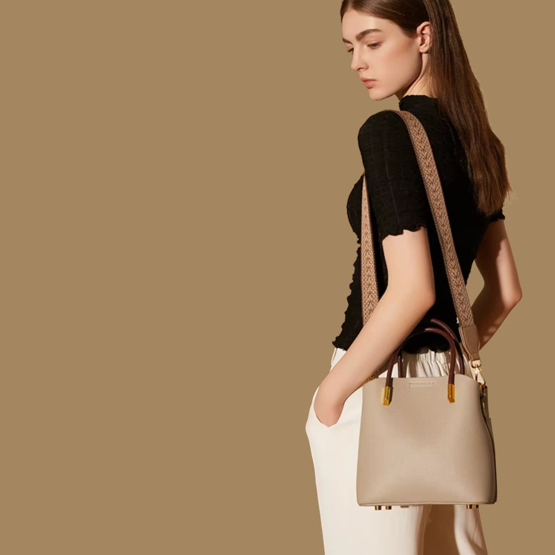 Luxe Bucket Carry beige luxury genuine leather handbag with upscale gold accents and premium wide woven strap worn on shoulder by model