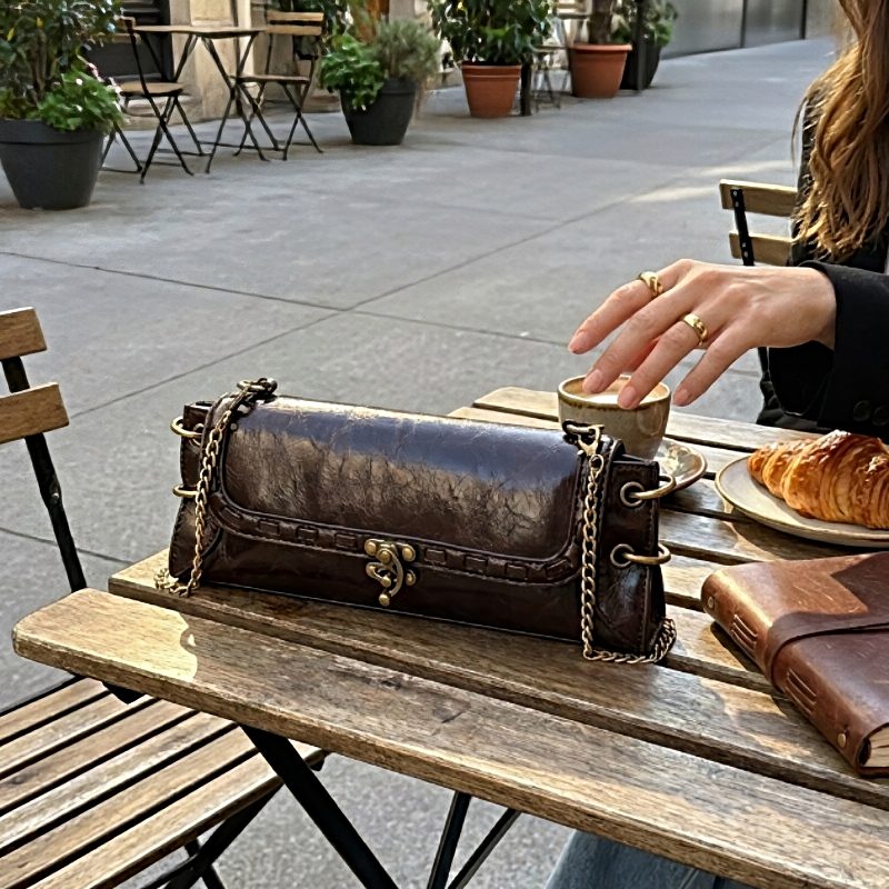 Luxe Chain Carry women’s vegan leather shoulder bag in dark brown with chain strap on café table
