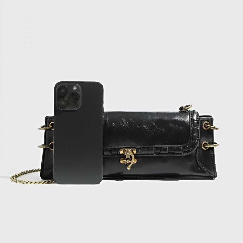 Luxe Chain Carry women’s black vegan leather crossbody bag with brass hardware and phone shown for scale