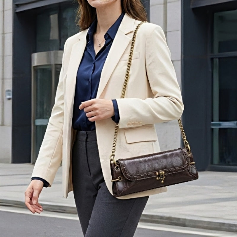 Luxe Chain Carry women’s vegan leather crossbody bag in dark brown with brass chain strap worn over the shoulder