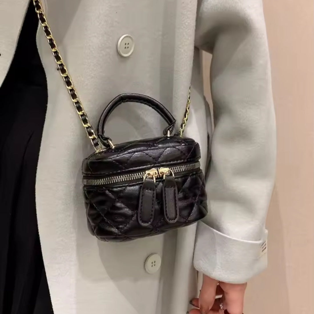 Timeless Petite Luxe crossbody bag in black luxury vegan leather with glossy finish elegant gold zipper and gold chain accented strap worn crossbody showcasing upscale lifestyle setting