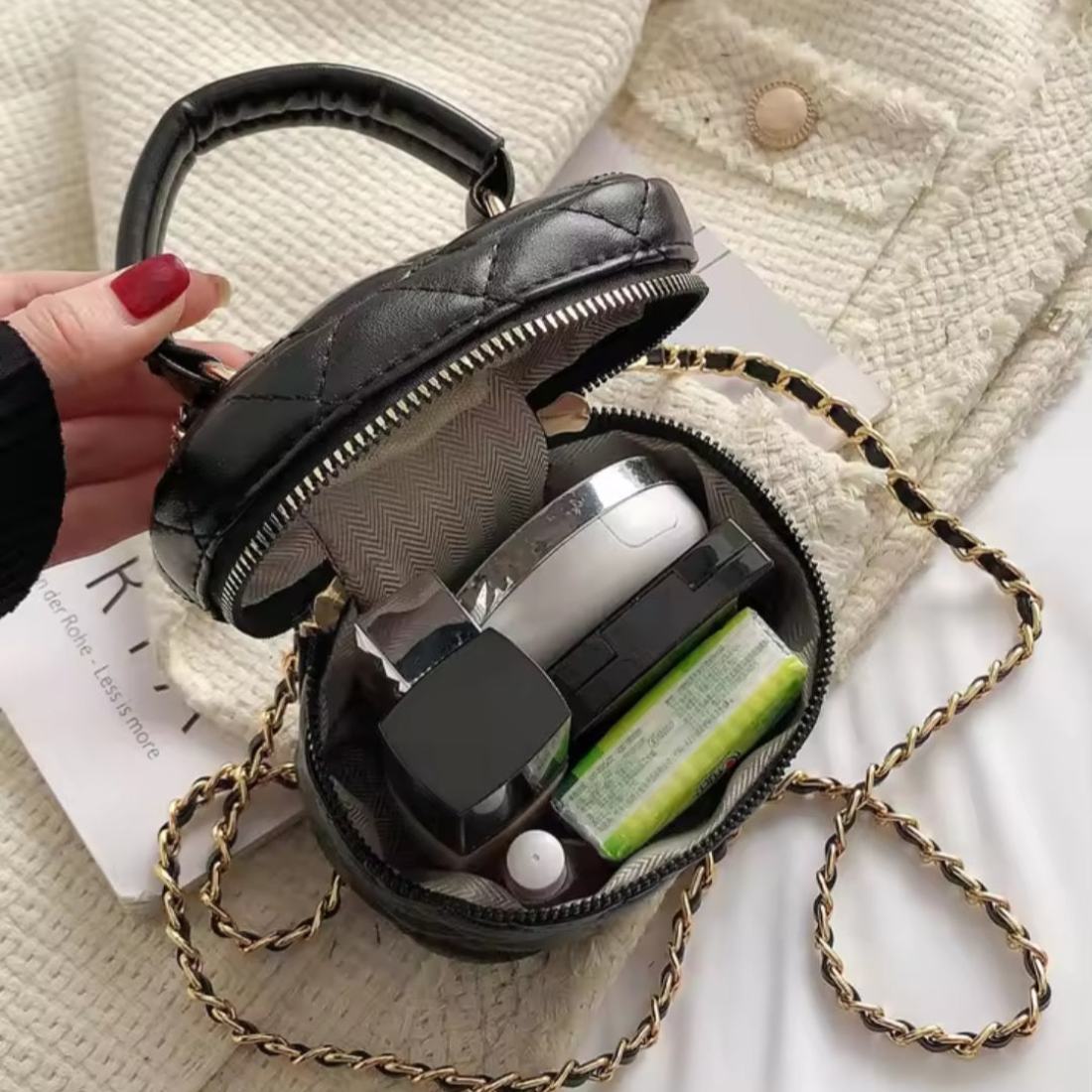 Timeless Petite Luxe black elegant crossbody bag in quilted luxury vegan leather with upscale gold and black chain strap open to reveal cosmetics and essentials held by hand showcasing elegant lifestyle setting