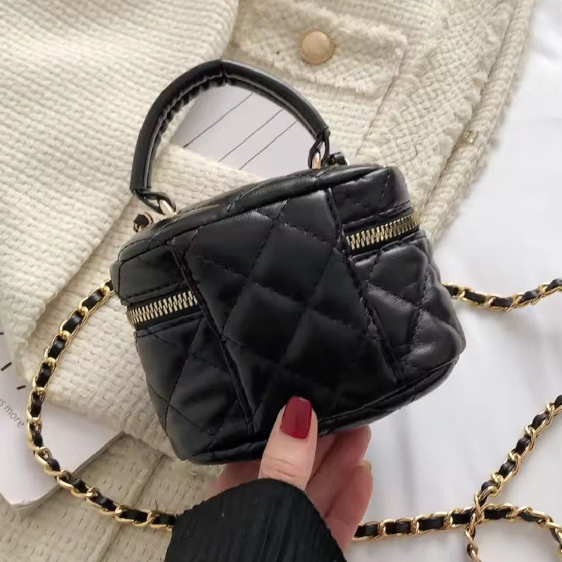 Timeless Petite Luxe crossbody bag in black quilted luxury vegan leather with elegant gold zipper and elegant gold chain strap accented held by hand showcasing upscale lifestyle setting