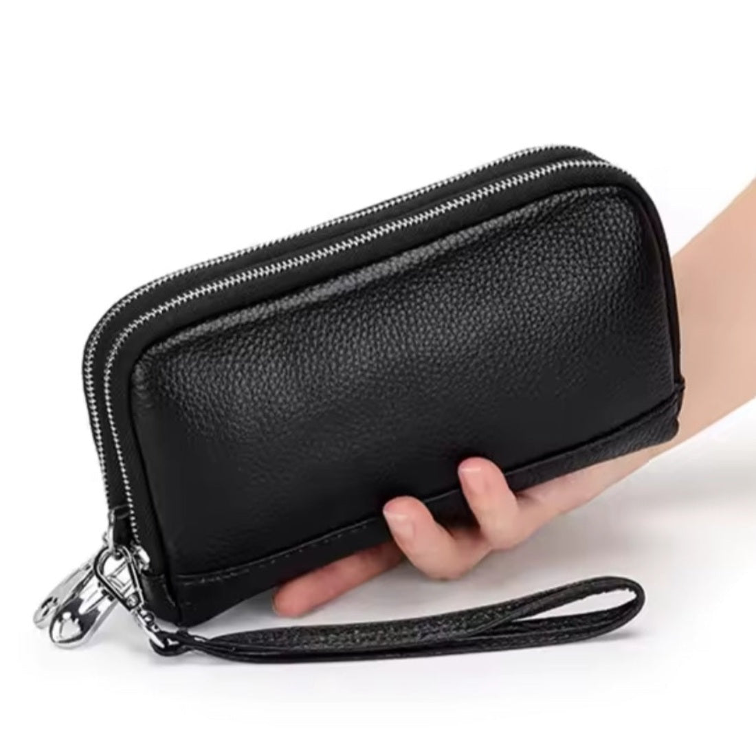 Signature Zip Companion wristlet wallet in black luxury genuine leather shown held by hand with visible dual zipper compartments and detachable wrist strap showcasing compact multi functional durable design and elegant everyday styling