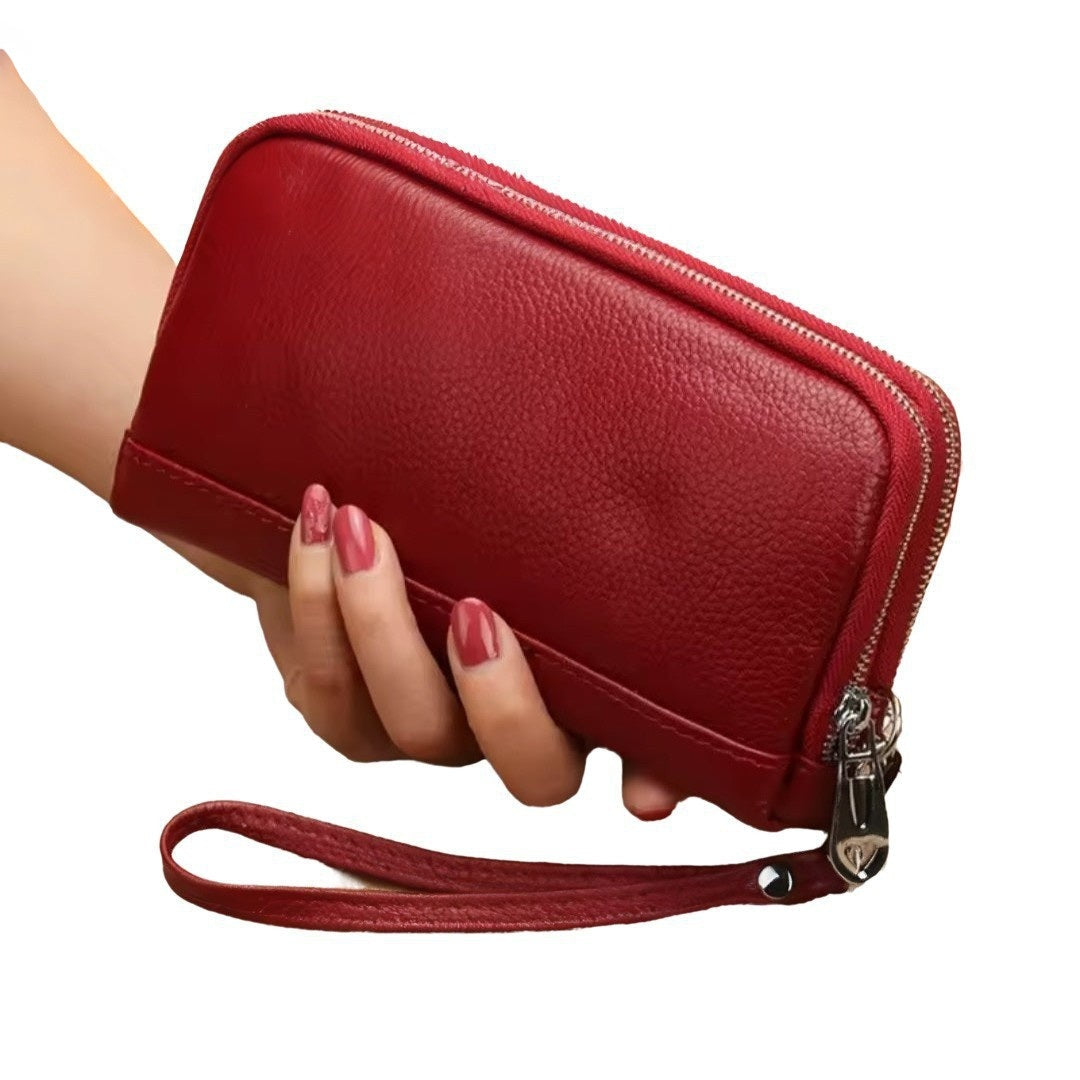 Signature Zip Companion wristlet wallet in red luxury genuine leather shown held by hand featuring textured surface upscale zip around closure and premium detachable wrist strap showcasing elegant styling and compact everyday durable functionality