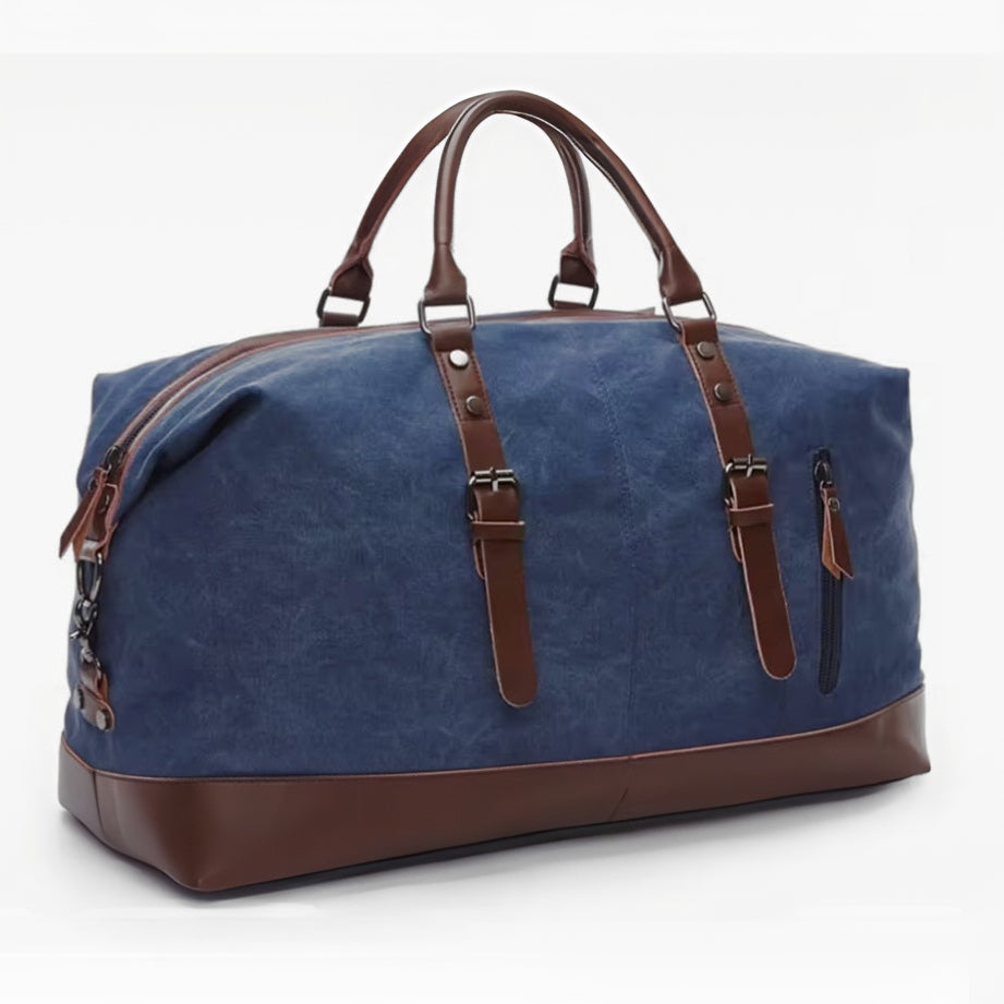 Timeless Travel Carry ag in blue durable canvas with genuine brown leather accents structured rectangular silhouette dual top handles adjustable detachable shoulder strap and reinforced leather base displayed showcasing luxury travel styling upscale craftsmanship premium finish and spacious carry on friendly design