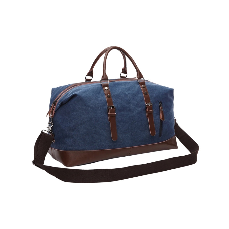 Timeless Travel Carry bag in blue durable canvas with genuine brown leather accents structured silhouette dual top handles adjustable detachable shoulder strap and leather zipper pulls showcasing luxury durable travel styling upscale craftsmanship premium finish and spacious carry on friendly design