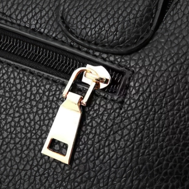 Urban Elegance Satchel  in black vegan luxury leather shown in close up view of back view gold tone zipper and rectangular pull tab with pebbled texture and visible stitching showcasing refined hardware detailing durable premium construction and elevated everyday functionality