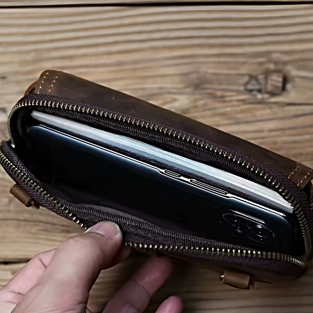 Heritage Utility Carry in dark brown crazy horse genuine leather with distressed oil wax finish partially open to reveal smartphone held by hand showcasing compact design and upscale everyday functionality